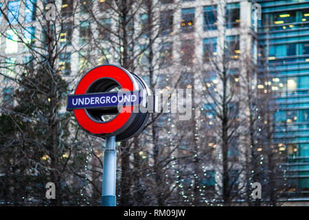 Canary Wharf London Underground Zeichen gegen das Licht und die Gebäude von Canary Wharf im Osten Londons Stockfoto