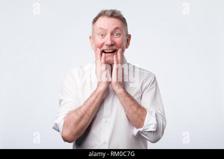 Älterer Mann sieht glücklich, froh, freudig weit Lächeln wie eine gute Nachricht zu hören Stockfoto