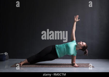 Junge Frau übt Yoga Asana Vasishthasana oder seitliche Liegestütz Stockfoto