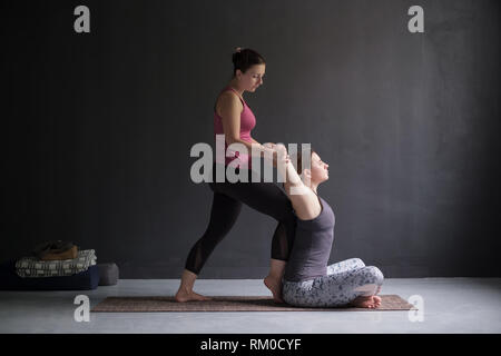 Frau helfen, ihre Freundin Schultern und Brust Yoga Asana zu öffnen. Stockfoto