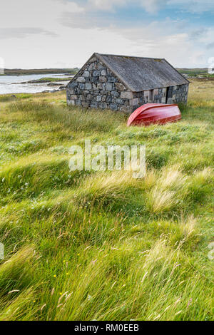 Traditionelle Steinhaus und roten Boot an der Küste, Uist, Äußere Hebriden, Schottland, Großbritannien, Europa Stockfoto