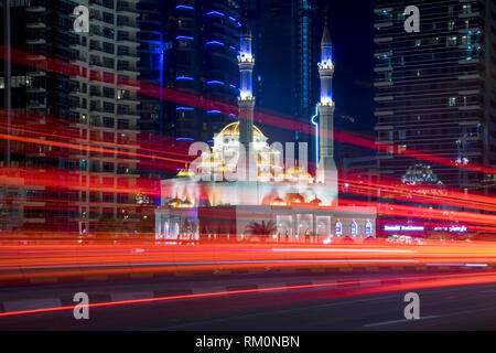 Die alten und modernen kollidieren in der futuristischen Stadt Dubai als Verkehr wirbelt Vergangenheit einer der vielen Moscheen. Stockfoto