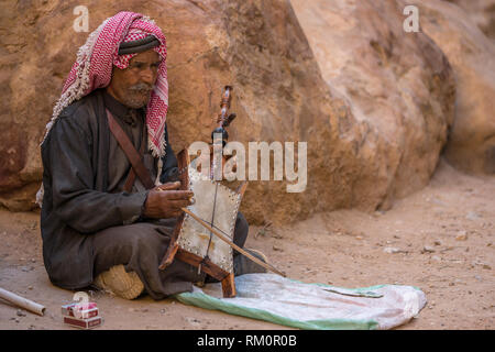 Beduinemann spielt eine rebab in einer felsigen Wadi in der Nähe von Petra in Jordanien. Stockfoto