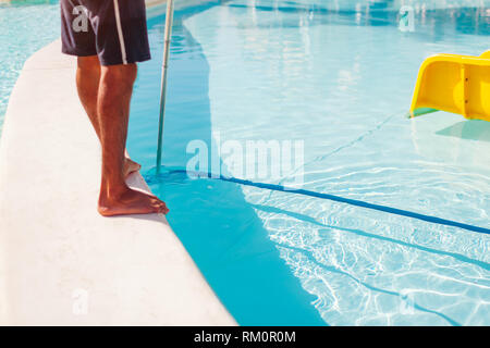 Mann Reinigung hotel Swimmingpool mit Vakuum Röhre Reiniger in den Morgen. Arbeitnehmer die Pflege von Pool Stockfoto