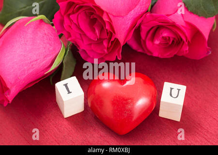 Rote Herzen und Rosen, und Holzwürfel mit Buchstaben I und U Ich liebe dich Konzept. Stockfoto