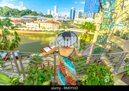 Touristische Frau mit breiten Hut suchen Panorama von der Terrasse über dem Clarke Quay und Riverside in Singapur, Südostasien Kreuzfahrt auf dem Singapore River Stockfoto