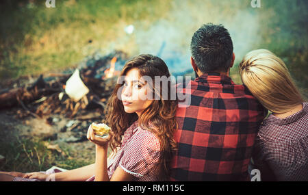 Eine Gruppe von Freunden mit Picknick im Sommer. Brunette Mädchen essen Green Apple während lehnte sich auf ihre Freundin. Vitamine, Gesundheit und Wohlbefinden Konzept Stockfoto