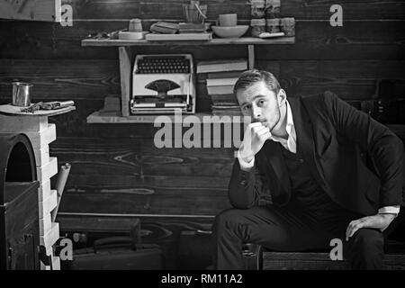 Intelligenter Kerl in der Studie Zimmer sitzen. Bärtige blonder Mann im blauen Anzug lehnte sich auf seine Hand beim Denken an eine Vorstellung Stockfoto