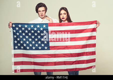 Paar auf ruhige Flächen hält Flagge der USA. Paar begrüßt die USA zu besuchen. Guy und Mädchen stolz, Amerikaner zu sein, grauen Hintergrund. Language School Konzept Stockfoto