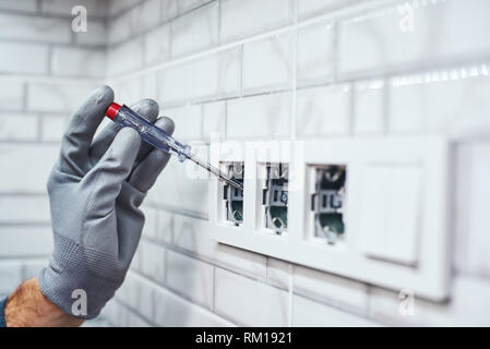 Elektrische Messung. Close-up senior Heimwerker neue Buchsen in der Küche in der Dunkelheit Stockfoto