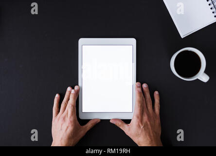 Ein Blick von Oben auf die männlichen Händen hält Tablet auf einem Schreibtisch. Kopieren Sie Platz. Stockfoto