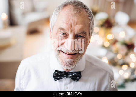 Eine Nahaufnahme Porträt einer älteren Mann stand im Innenraum in einem Zimmer für eine Partei. Stockfoto