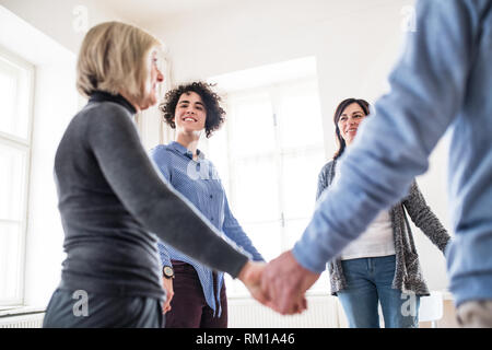 Gruppe von Menschen in einem Kreis stehen und halten sich an den Händen, während der Therapie. Stockfoto