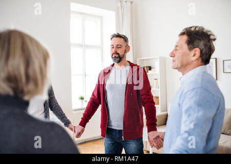 Gruppe von Menschen, die mit geschlossenen Augen stehen im Kreis und halten sich an den Händen, während der Therapie. Stockfoto