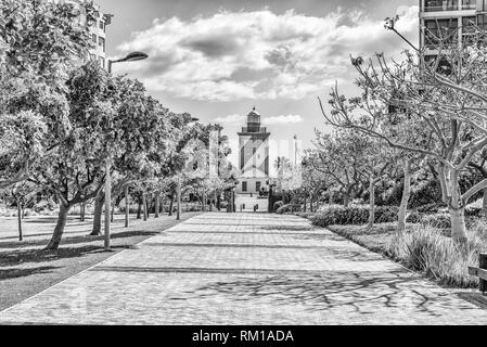 Kapstadt, Südafrika, 17. AUGUST 2018: ein Gehweg, mit dem Greenpoint Leuchtturm sichtbar, im Green Point Park in Kapstadt. Schwarzweiß Stockfoto
