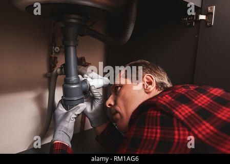 Waschbecken syphon reparieren. In der Nähe von seniour Heimwerker Instandsetzung Waschbecken in der Küche Stockfoto