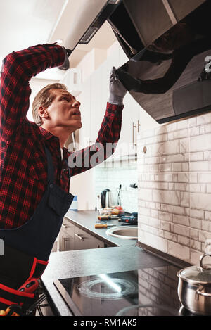 Erste technische Hilfe. Junger Mann Reparaturen mit Küchenausstattung Abzugshaube Stockfoto