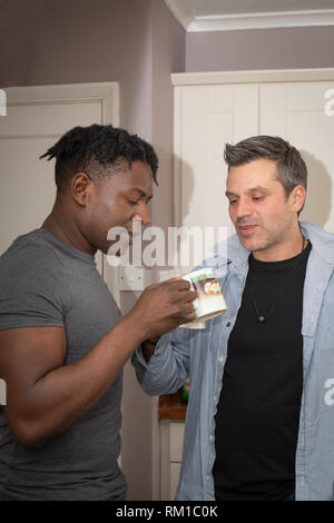 Ein homosexuelles Paar Geschichten von Ihren Tag bei der Arbeit über eine Scheibe Toast und eine Tasse Tee und Kaffee am Abend. Stockfoto