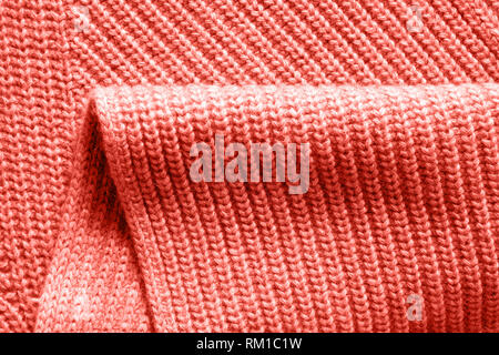 Warme Wolle aus Gewirken Kleider Hintergrund mit Falten in einer Trendfarbe des Jahres 2019 Lebende Korallen Pantone. Stockfoto