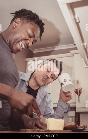 Ein homosexuelles Paar Geschichten von Ihren Tag bei der Arbeit über eine Scheibe Toast und eine Tasse Tee und Kaffee am Abend. Stockfoto