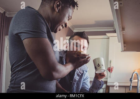 Ein homosexuelles Paar Geschichten von Ihren Tag bei der Arbeit über eine Scheibe Toast und eine Tasse Tee und Kaffee am Abend. Stockfoto