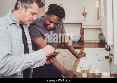 Ein homosexuelles Paar Geschichten von Ihren Tag bei der Arbeit über eine Scheibe Toast und eine Tasse Tee und Kaffee am Abend. Stockfoto