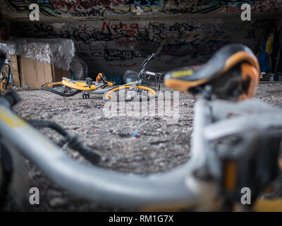 Alte gelbe Schrott, Fahrräder unter Beton Treppe mit Graffiti und Obdachlose schlafen Tierheim Stockfoto