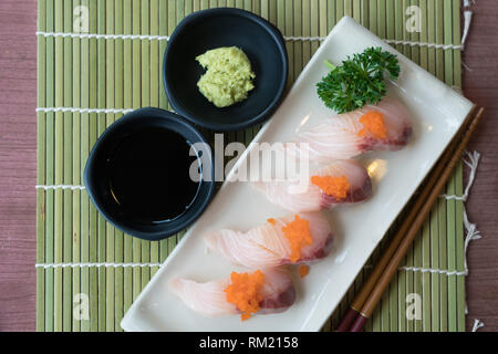 Hamachi Sushi auf weiße Platte zusammen mit japanischen Sauce und green leaf Dekoration, Japanisches Essen, Ansicht von Oben im Sushi Stockfoto