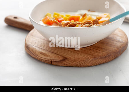 Gesundes Frühstück. Multigrain Flakes mit griechischen Joghurt und Früchte Mango und Papaya Nahaufnahme Stockfoto