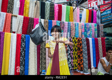 YANGON, MYANMAR - 3. JANUAR 2016: Ein unbekannter Junge Mädchen Verkauf von Stoffen auf dem Markt in Yangon, Myanmar. Stockfoto