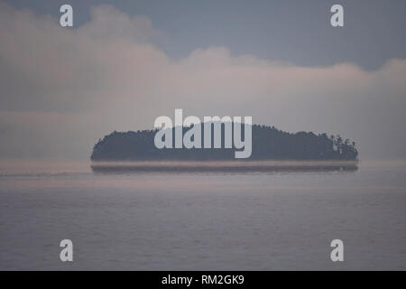 Insel Erscheinen aus dem Morgennebel am See in Saganaga Quetico Provincial Park in Ontario Stockfoto