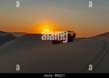 Silhouette einer Buggy mit Touristen bei Sonnenuntergang in den küstennahen peruanischen Wüste zwischen Ica und Huacachina, Peru. Stockfoto