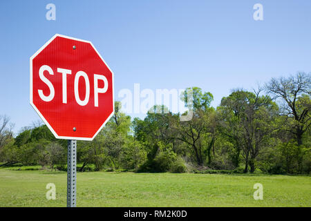 Stop-Schild mit grünen Bäumen und Feld Stockfoto