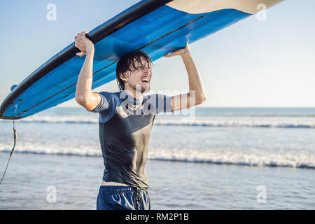 Mann, Surfbrett über seinen Kopf. Nahaufnahme von hübscher Kerl mit Surfbrett auf dem Kopf am Strand. Portrait von Mann Surfboard auf hid Kopf und Stockfoto