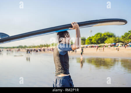 Mann, Surfbrett über seinen Kopf. Nahaufnahme von hübscher Kerl mit Surfbrett auf dem Kopf am Strand. Portrait von Mann Surfboard auf hid Kopf und Stockfoto