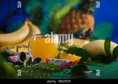 Tropische Früchte frischen Saft auf einem blauen Hintergrund mit Bananen, Ananas, Mango und Drachenfrucht. Exotischen drink Header mit Kopie Raum Stockfoto
