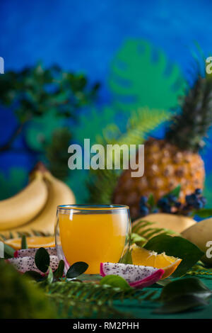Tropische Früchte frischen Saft auf einem blauen Hintergrund mit Bananen, Ananas, Mango und Drachenfrucht. Exotischen drink Konzept mit Kopie Raum Stockfoto