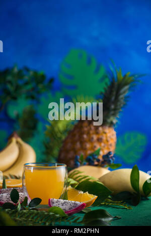 Tropische Früchte frischen Saft auf einem blauen Hintergrund mit Bananen, Ananas, Mango und Drachenfrucht. Exotischen drink Konzept mit Kopie Raum Stockfoto