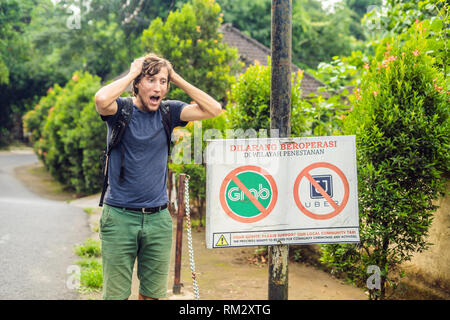 BALI, Indonesien - 21. Mai, 2018: Der junge Mann sieht Protest Zeichen an der Wand in der Indonesischen Uber und Taxifahrer Greifer Einwand lautet "Uber und Greifer Stockfoto