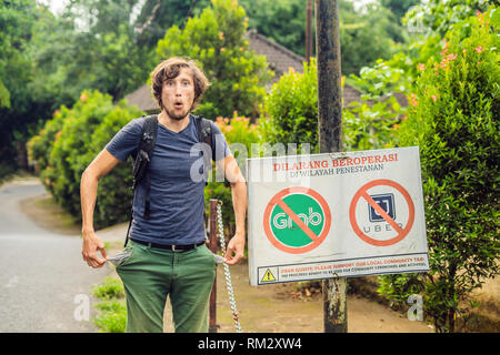 BALI, Indonesien - 21. Mai, 2018: Der junge Mann sieht Protest Zeichen an der Wand in der Indonesischen Uber und Taxifahrer Greifer Einwand lautet "Uber und Greifer Stockfoto