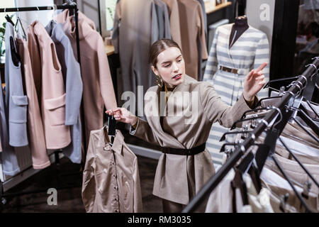 Die jungen Langhaarigen hübsche Frau mit großen Ohrringe wählen trendy Shirts Stockfoto