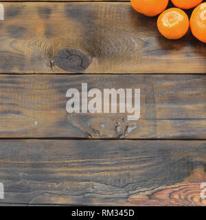 Viel frische Orangen Mandarinen liegen auf einem braunen Holz- Hintergrund. Flach mit Früchten in einem hölzernen Kasten Stockfoto