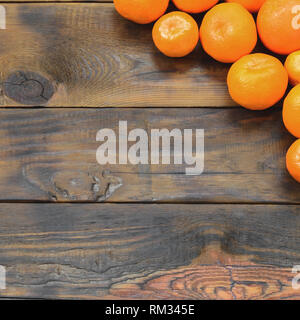 Viel frische Orangen Mandarinen liegen auf einem braunen Holz- Hintergrund. Flach mit Früchten in einem hölzernen Kasten Stockfoto