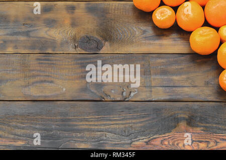 Viel frische Orangen Mandarinen liegen auf einem braunen Holz- Hintergrund. Flach mit Früchten in einem hölzernen Kasten Stockfoto