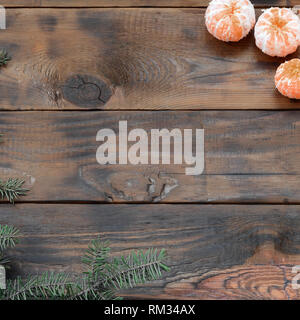 Eine Menge Orangen Mandarinen und Weihnachten Tannenzweigen liegen auf einem braunen Holzplanken. Neue Jahre flach Hintergrund Stockfoto