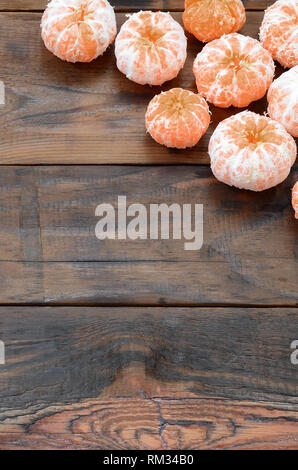 Viel frische Orangen Mandarinen liegen auf einem braunen Holz- Hintergrund. Flach mit Früchten in einem hölzernen Kasten Stockfoto