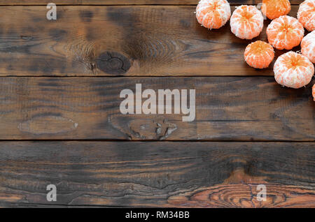 Viel frische Orangen Mandarinen liegen auf einem braunen Holz- Hintergrund. Flach mit Früchten in einem hölzernen Kasten Stockfoto