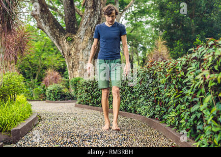 Menschen gehen auf eine strukturierte, mit Kopfstein Pflaster, Reflexzonenmassage. Pebble Stones auf dem Bürgersteig für Fußreflexzonenmassage Stockfoto