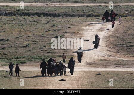 Deir Ezzor, Syrien. 12 Feb, 2019. Frauen gehen mit ihren Kindern als Zivilisten der islamische Staat fliehen - statt Dorf Baghouz im östlichen syrischen Provinz von Deir Ezzor. Mehr als 1.500 Menschen haben im vergangenen pocket Islamischen Staat im östlichen Syrien in den letzten 48 Stunden Links zu fliehen, die Schlacht zwischen den Kämpfern der syrischen Demokratischen Kräfte (SDF), einer von den USA unterstützten Kurdischen-Gruppe führte, und der Islamischen Staat. Credit: Aboud Hamam/dpa/Alamy leben Nachrichten Stockfoto