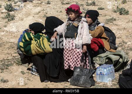 Deir Ezzor, Syrien. 12 Feb, 2019. Eine Frau und ihre Kinder nehmen einen Rest als Zivilisten der islamische Staat fliehen - statt Dorf Baghouz im östlichen syrischen Provinz von Deir Ezzor. Mehr als 1.500 Menschen haben im vergangenen pocket Islamischen Staat im östlichen Syrien in den letzten 48 Stunden Links zu fliehen, die Schlacht zwischen den Kämpfern der syrischen Demokratischen Kräfte (SDF), einer von den USA unterstützten Kurdischen-Gruppe führte, und der Islamischen Staat. Credit: Aboud Hamam/dpa/Alamy leben Nachrichten Stockfoto